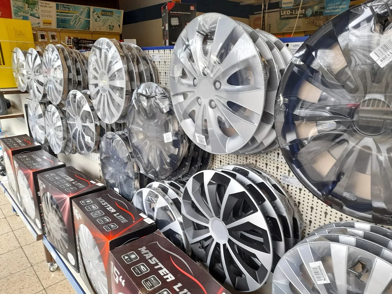 Wand mit Radkappen in verschiedenen Größen im Laden von KFZ-Teile Neubauer